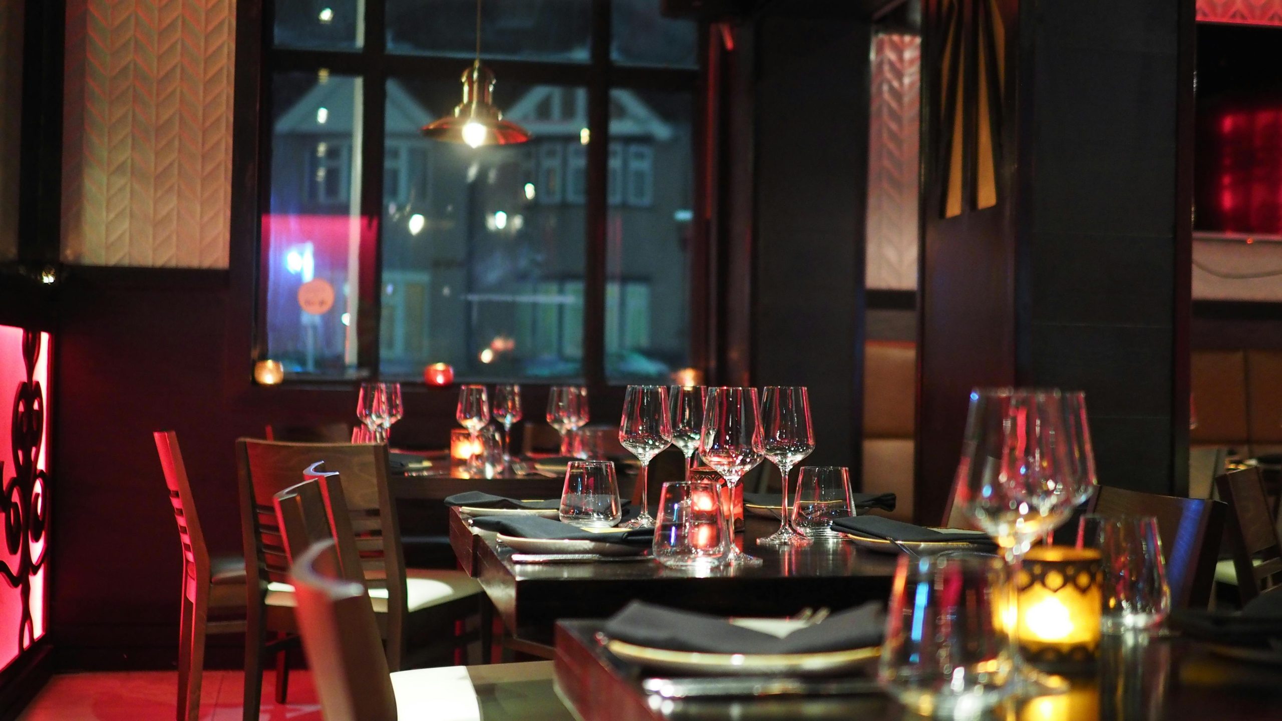 Interior de un restaurante de lujo con varias mesas y copas preparadas para los comensales