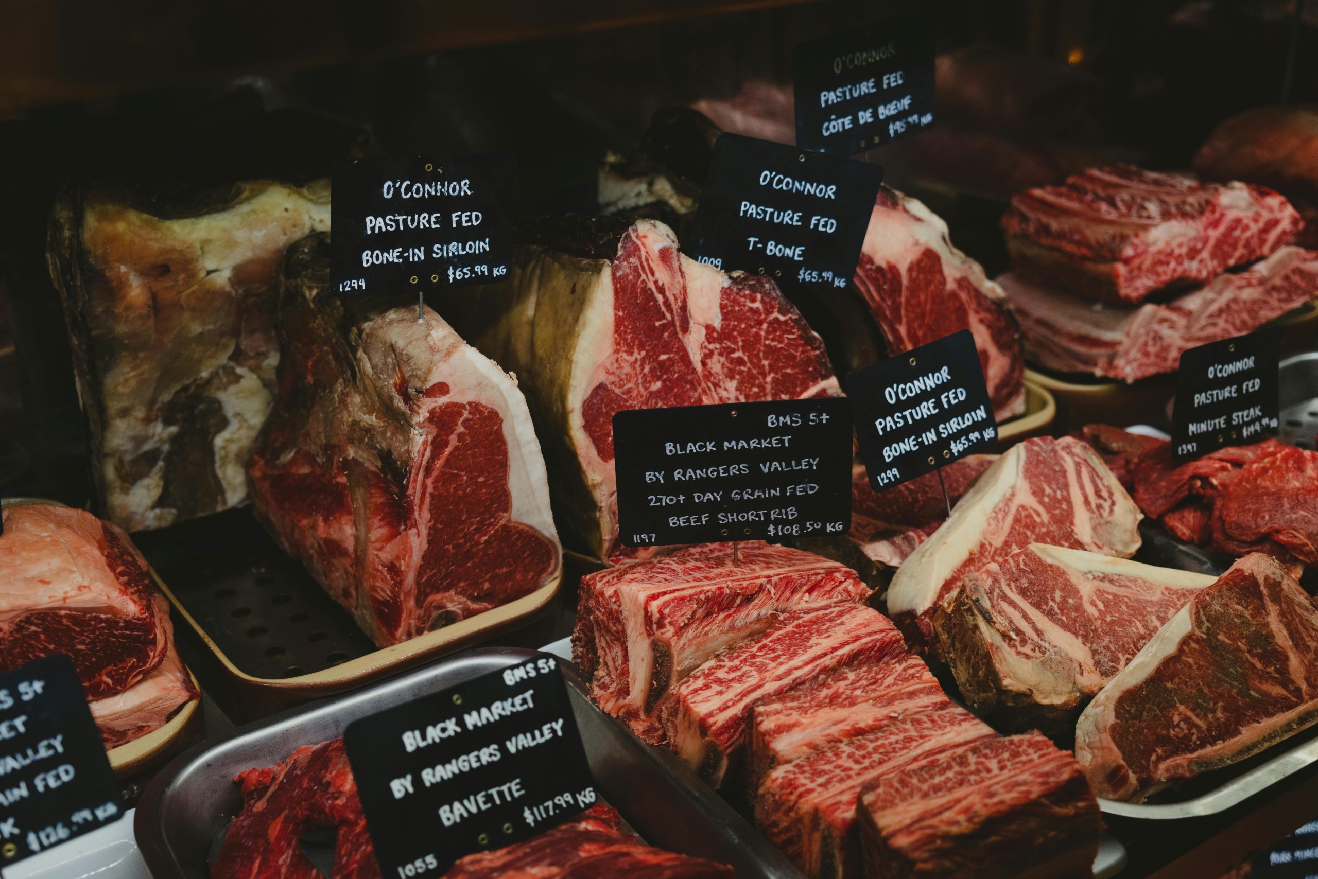 Cortes de carnes en un mostrador con precios y nombres en Inglés